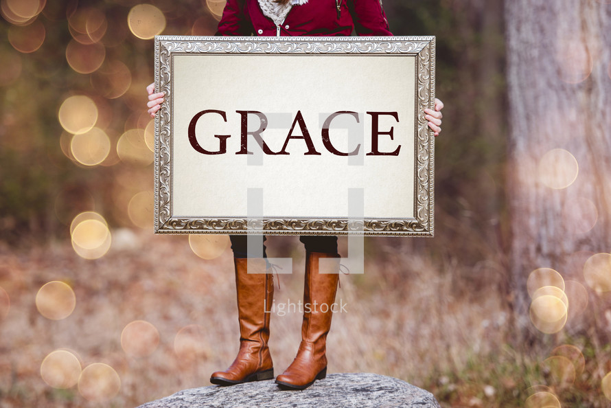 a woman holding a sign the reads grace 