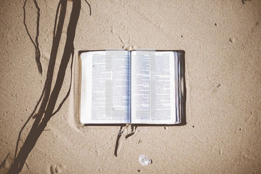 opened Bible in the sand 