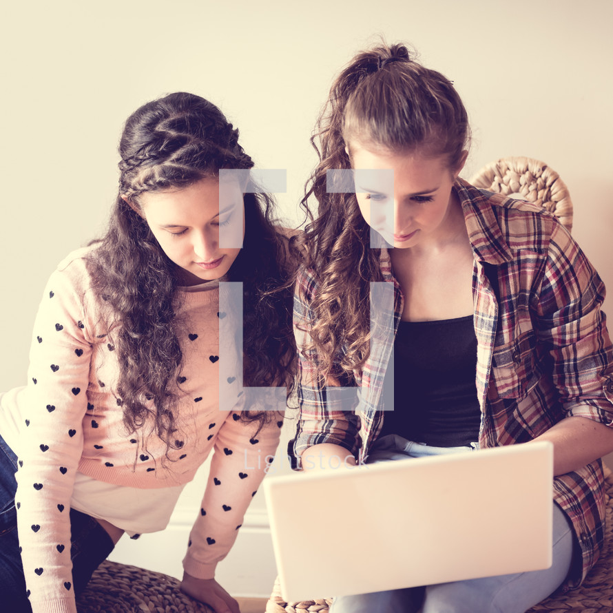 teen girls typing on a laptop computer 