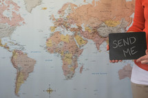 world map and woman holding a send me sign 