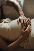 a pregnant couple holding hands on the belly