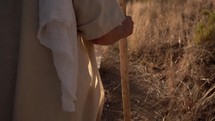Jesus or a Bible prophet walking in the desert with his staff