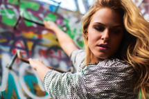 a woman climbing up a graffiti covered wall 