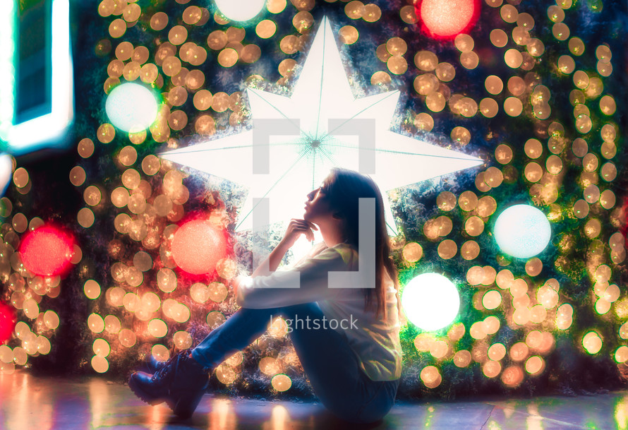 a woman sitting in front of a Christmas tree