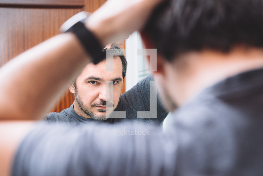 man combing his hair in the mirror 