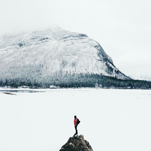 snow on a mountain and woman standing on a rock peak 