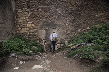 Man entering a doorway in the side of a rocky hillside.