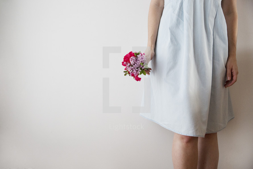A girl in a white dress holding a bouquet of flowers.