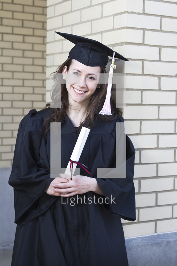 College student at graduation with a diploma, cap, and gown