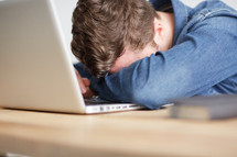 a person with his head on a his laptop computer keyboard 