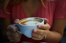 a woman holding a cappuccino mug 