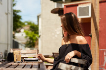 a woman reading a Bible and iced coffee on a wooden table outdoors 