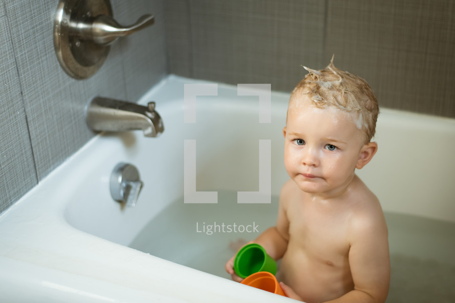 a toddler boy in the bathtub 