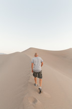 a man standing on desert sand dunes 