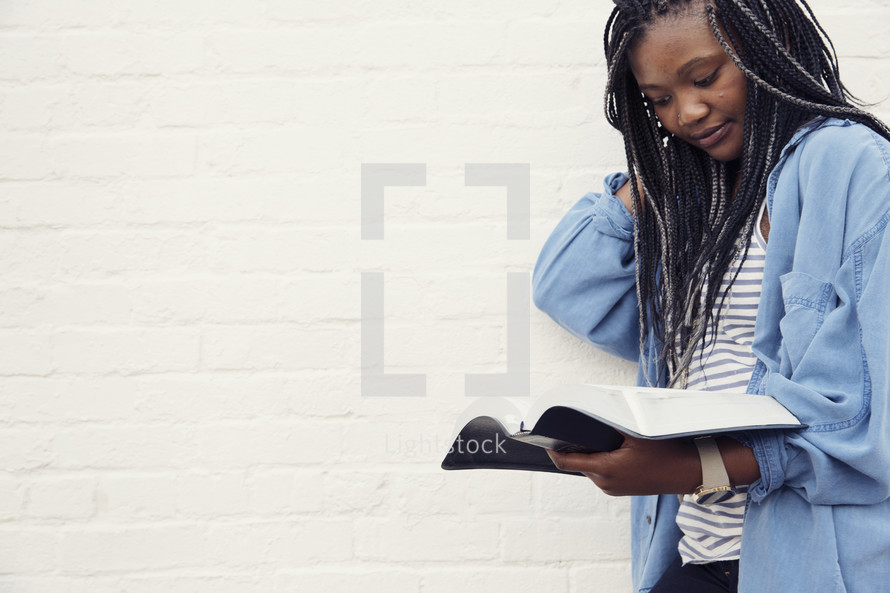 A young woman standing and reading the Bible 