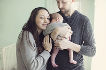 Husband and wife hold infant.