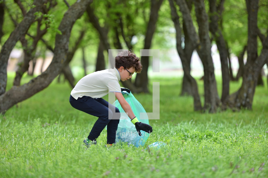 a boy picking up trash in a park 