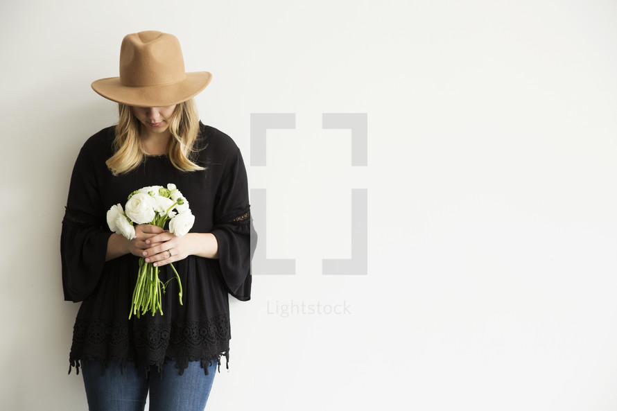 a woman holding flowers and looking down 