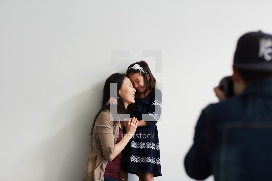 photographer taking a picture of a mother and daughter in studio 
