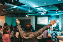 man with hands raised during a worship service 