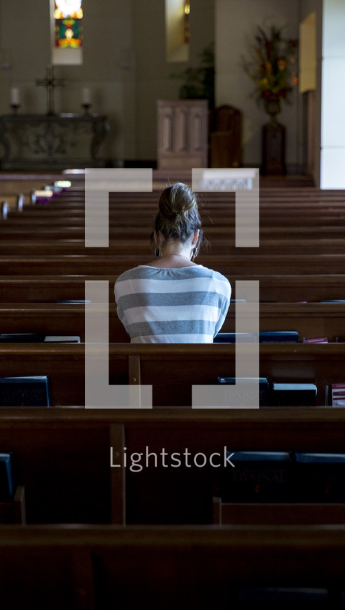 a woman in prayer in an empty church 