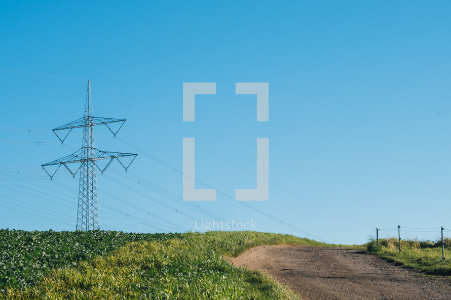 Electrical tower in rural farm with dirt path