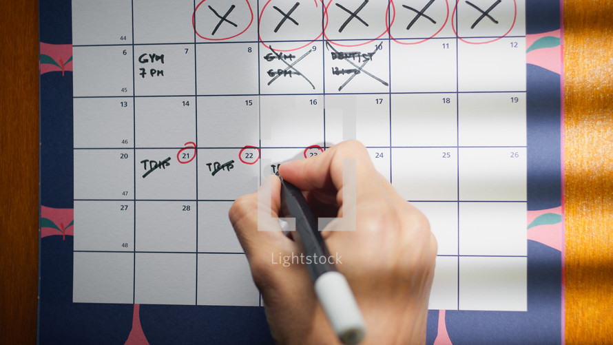 Hand is marking important dates on the calendar
