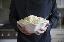 a man holding a bowl of mashed potatoes 