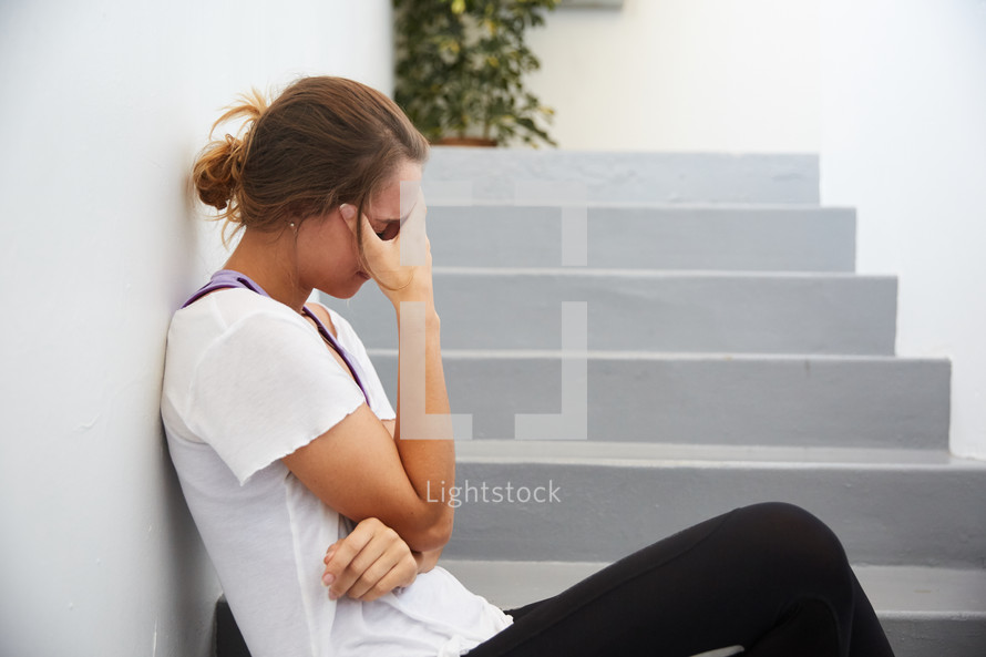 a stressed woman sitting on steps outdoors 