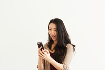 a woman looking at her cellphone and smiling 