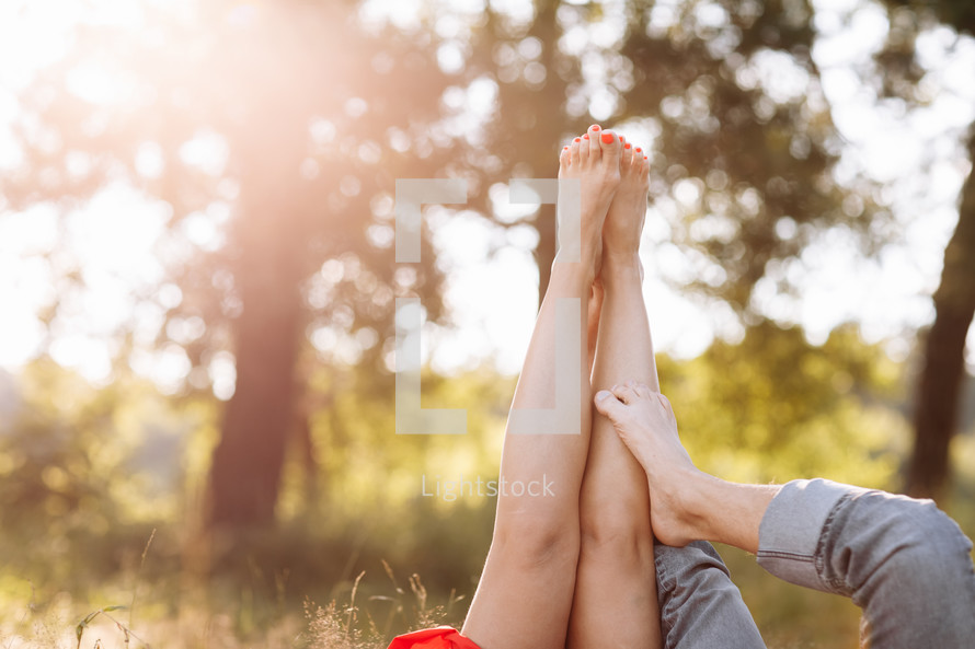 couple in love lying in the grass and lifting their legs up. summer sunny day.