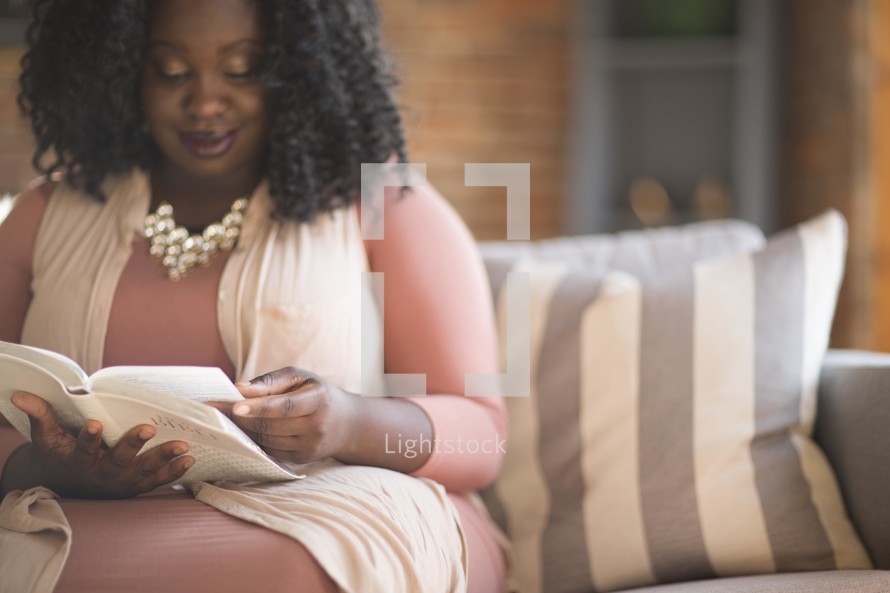 woman sitting on a couch reading a Bible 