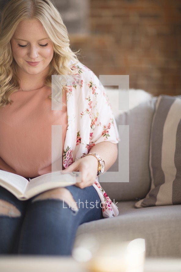 woman sitting on a couch reading a Bible 