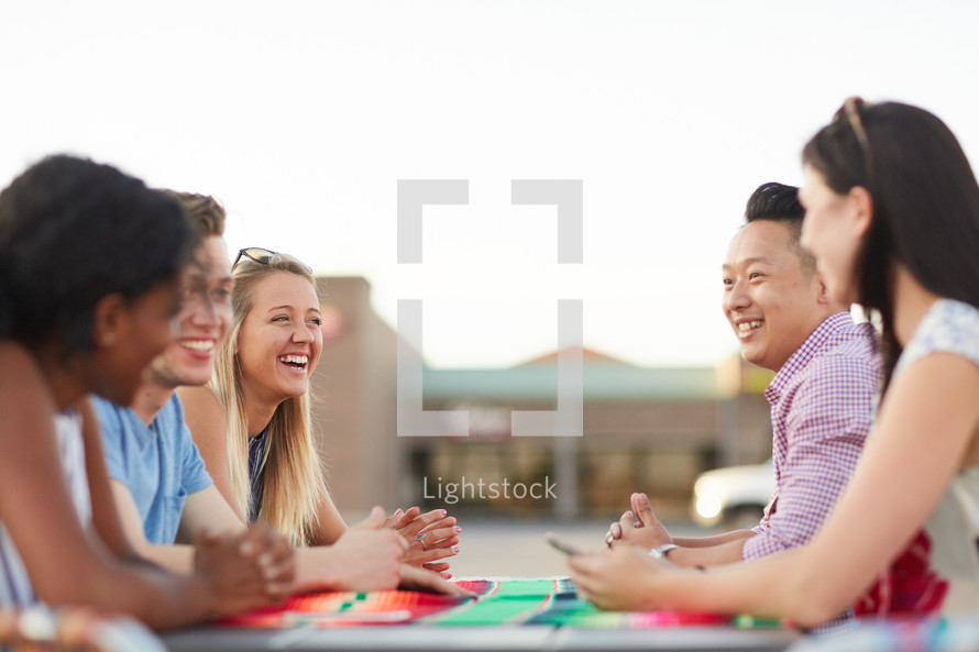 friends talking around an outdoor table 