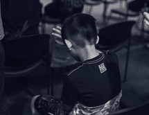 a child sitting in a worship service with his hand raised 