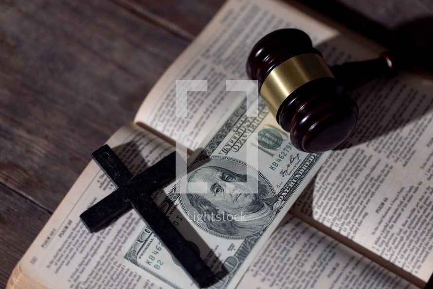 Bible and gavel with money and cross