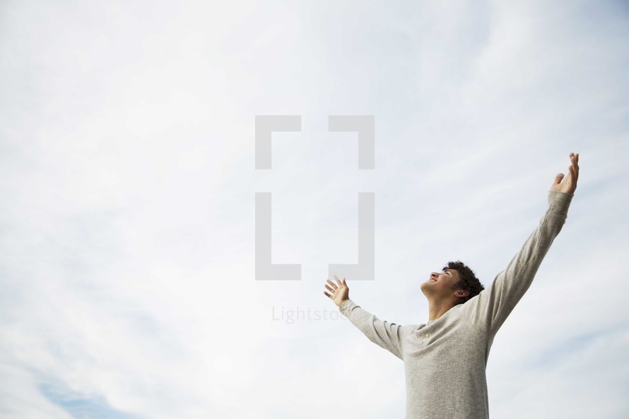 teen boy with his hands raised in praise 