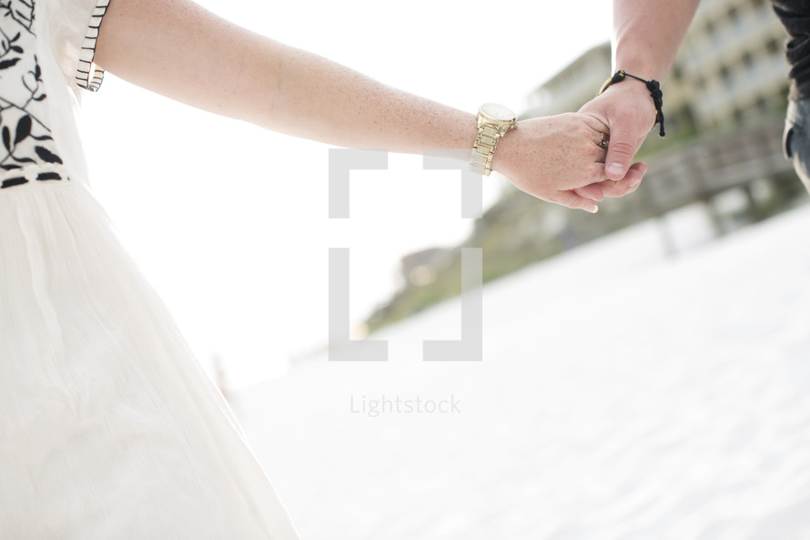 man and a woman holding hands on a beach 