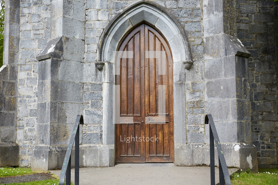 grand arched wooden door on a stone cathedral 