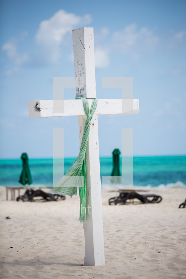 white cross on a beach and lounge chairs 