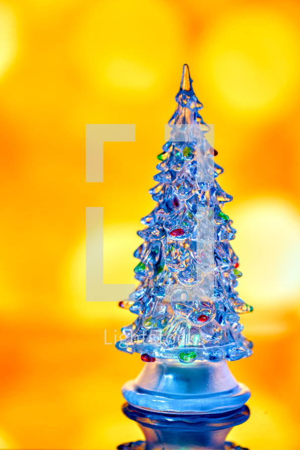 Miniature transparent Christmas tree isolated on golden bokeh light
