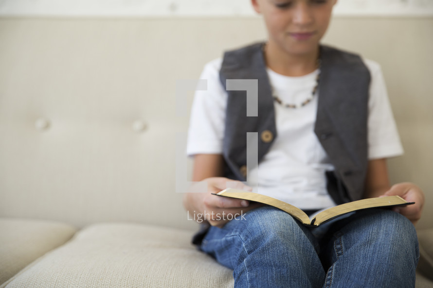 a boy child sitting reading a Bible 