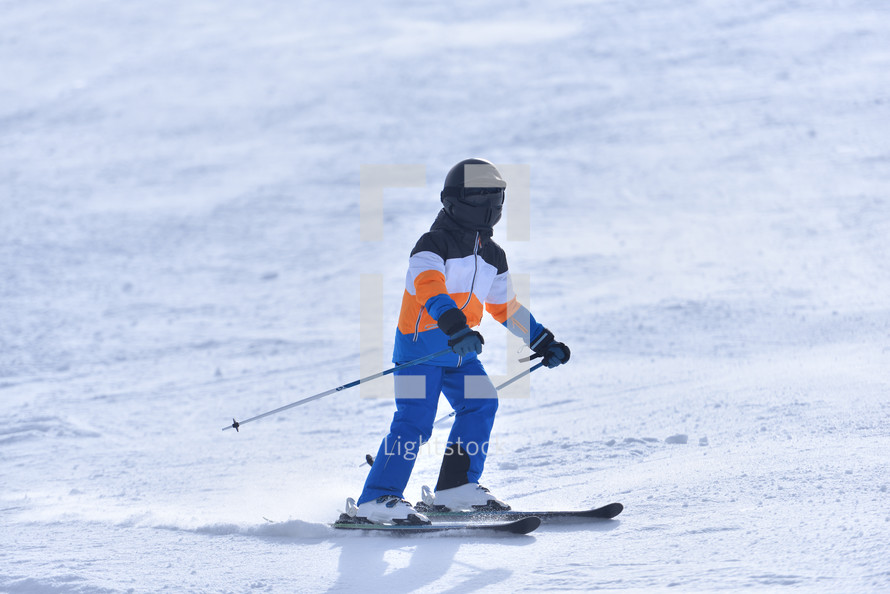 Young Skier Traveling Down a Sunny Slope 