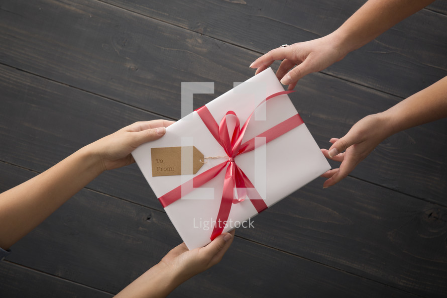 One person giving a wrapped gift  to another.