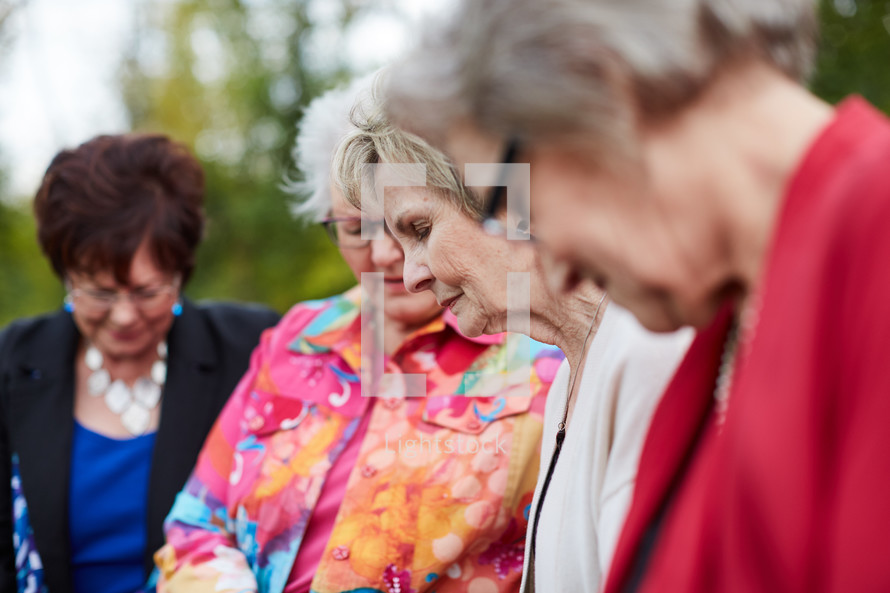 older women praying together outside.
