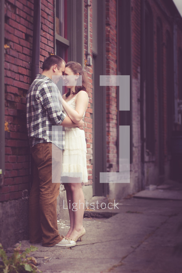 a couple embracing outdoors in front of a brick building 