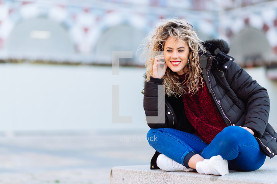 curly blonde woman sitting on bench. Casual clothes