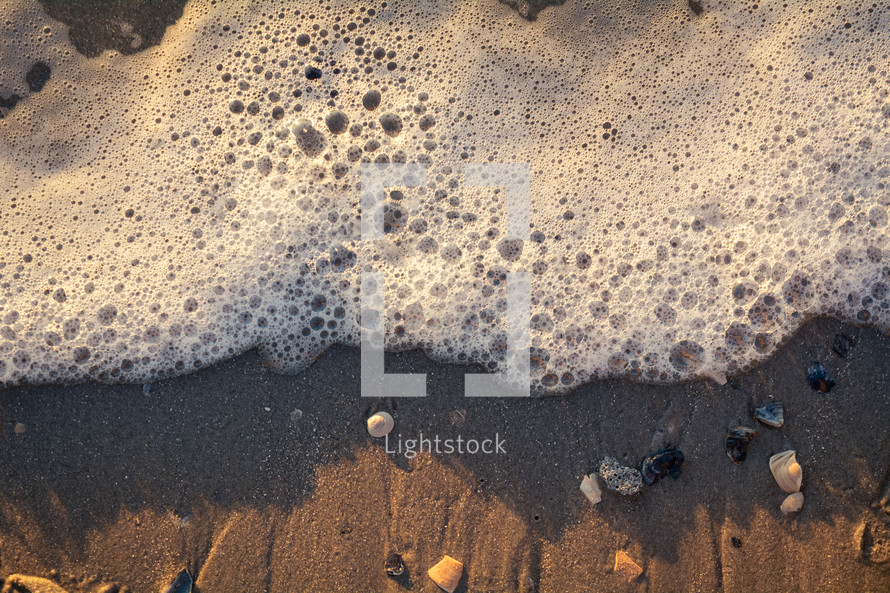sea foam washing onto a beach 
