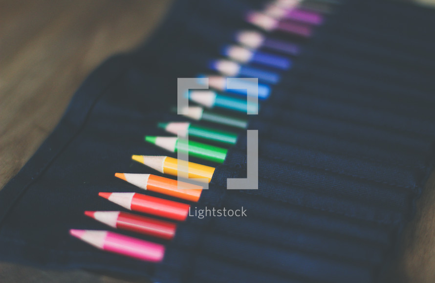 colored pencils in a black apron 