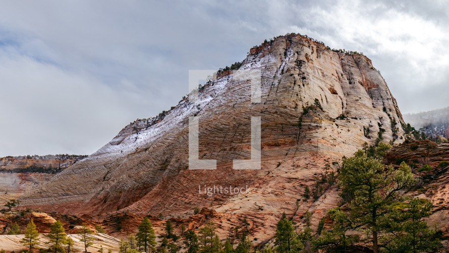 A view of a sandstone mountain in Zion National park with snow.